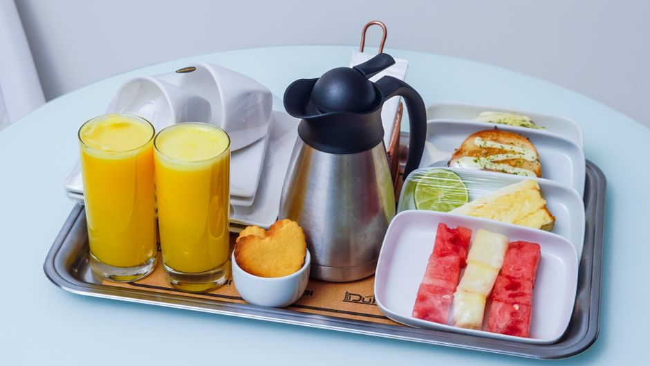 A well-presented hotel breakfast tray with fresh orange juice, fruits, and pastries, ideal for travel imagery.