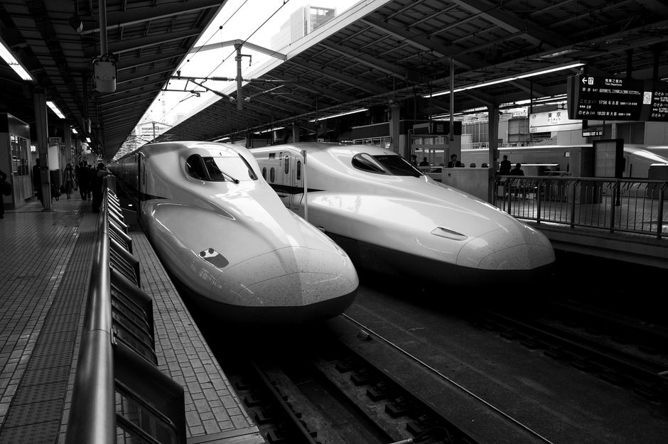 Black and white photo of Shinkansen trains at a busy Tokyo station platform.
